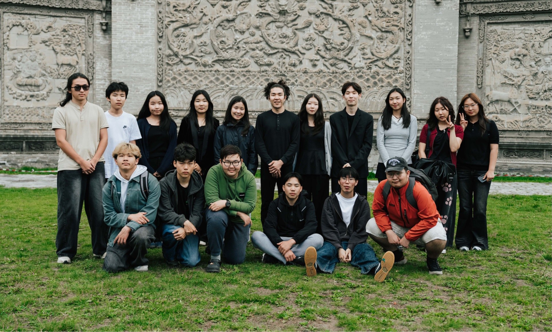 MindMaze coding students and mentors gathered in front of a carved stone wall
