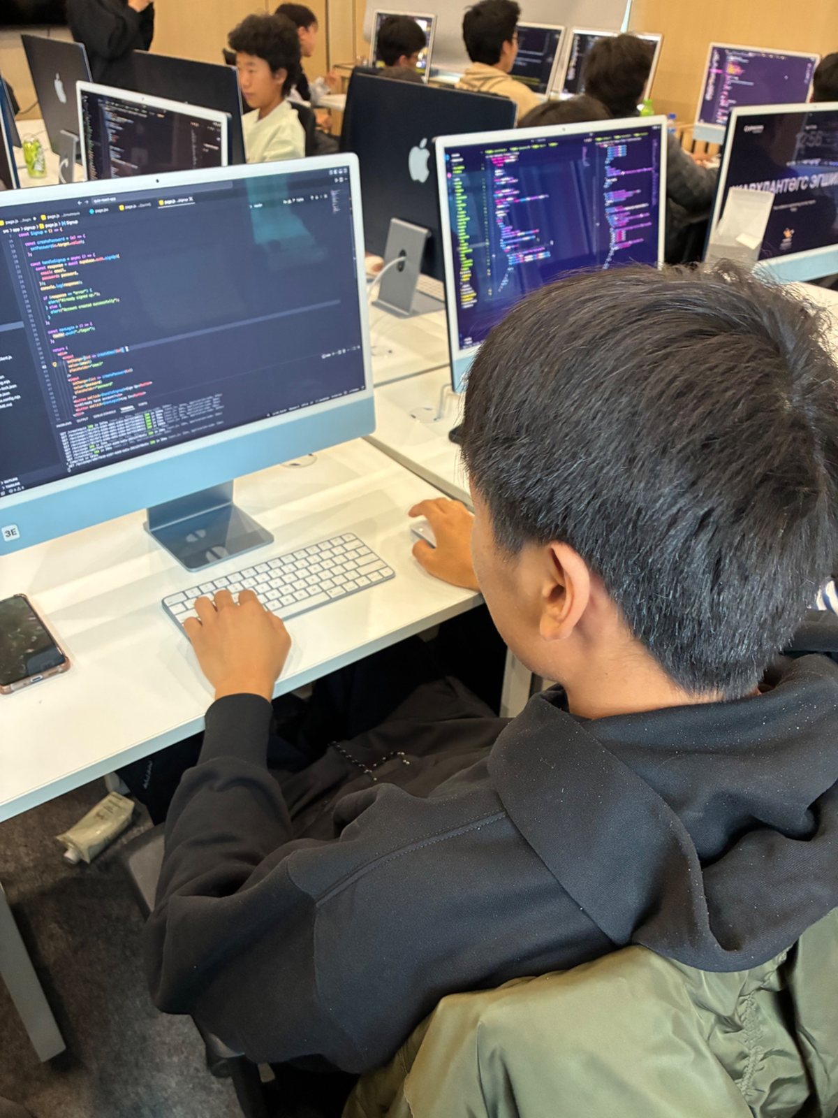 A student writes code at an iMac during a weekend class